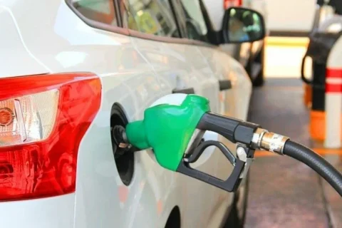 Білий автомобіль заправляють зеленим пістолетом на АЗС